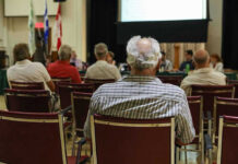 The event is back. The controversy isn’t over. People attending a meeting in a conference room.