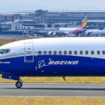 Boeing 737-800 on airport runway with other planes.