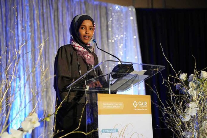 Woman in hijab speaking at a podium on a decorated stage