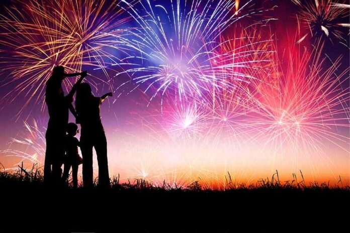 Silhouetted figures watching a colorful fireworks display against a twilight sky