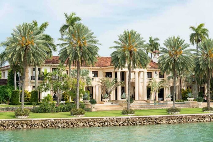 shutterstock_199184924 A luxurious mansion surrounded by palm trees and a waterfront view