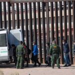 New Border Crackdown Targets Illegal Reentry Border agents escort a group near a tall fence and a patrol van