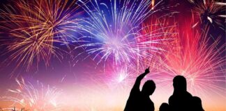 Silhouetted figures enjoying a fireworks display against a colorful night sky