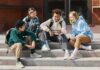 Group of teens sitting on outdoor steps looking at a phone