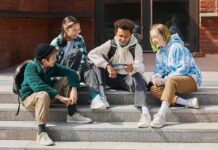 Group of teens sitting on outdoor steps looking at a phone