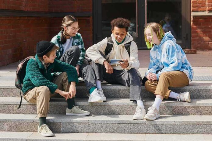 Group of teens sitting on outdoor steps looking at a phone