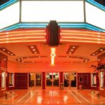 Banned Flick Explodes: From Hollywood Rejection to Viral Hit Entrance of a vintage movie theater illuminated by neon lights at night
