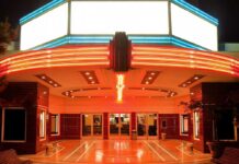 Banned Flick Explodes: From Hollywood Rejection to Viral Hit Entrance of a vintage movie theater illuminated by neon lights at night