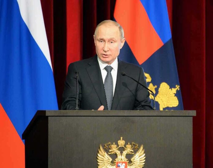 shutterstock_1038561886 man in suit speaking at a podium with flags behind him