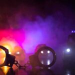 Handcuffs on a surface with police cars and flashing lights in smoky darkness