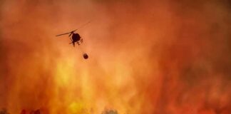 Helicopter fights massive wildfire over burning forest
