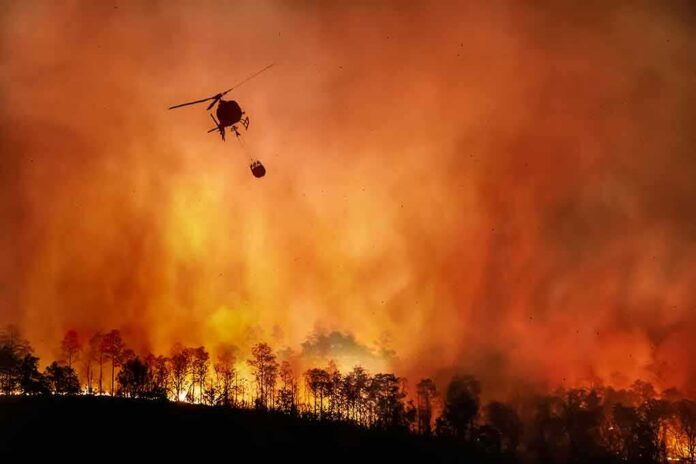 shutterstock_1810018291 Helicopter fights massive wildfire over burning forest