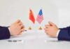 U.S.–China Tensions Rise for Urgent Diplomacy Two diplomats sit across table with China and United States flags between them