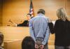 Hidden for Years: Mother Found in Living Room Freezer Defendant in handcuffs stands before a judge in a courtroom