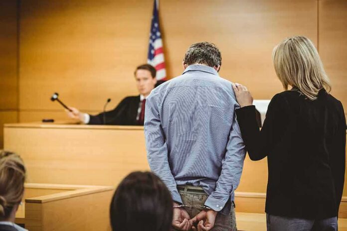 shutterstock_243765985 Defendant in handcuffs stands before a judge in a courtroom