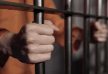California Approves Murder Parole hands gripping prison bars