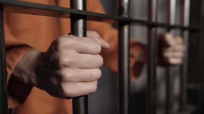 shutterstock_413184934 hands gripping prison bars