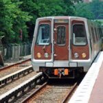 Senator Nearly Hit by Passing Train at Rail-Safety Event Metro train arriving at a station surrounded by greenery
