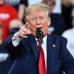 Endless Bombing? Trump Warns of More Iran Strikes Man in suit pointing, speaking at a rally.