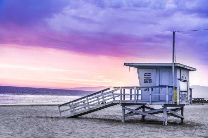 Lifeguard tower on a sandy beach at sunset with colorful sky