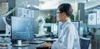 Engineer in lab coat working at a computer in a modern lab