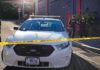 Aaron Guiel near police car behind yellow caution tape