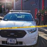 Aaron Guiel near police car behind yellow caution tape