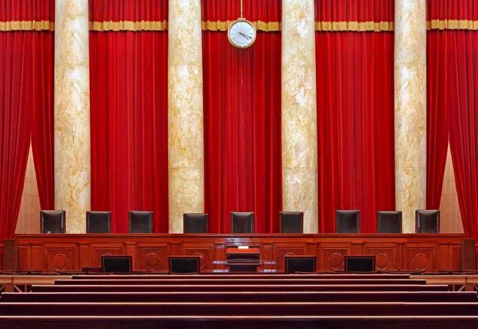 shutterstock_1174908838 Supreme court courtroom with red curtains and empty judges' bench