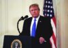 Cabinet Official’s Gesture Draws Scrutiny man at podium with microphone and US flag