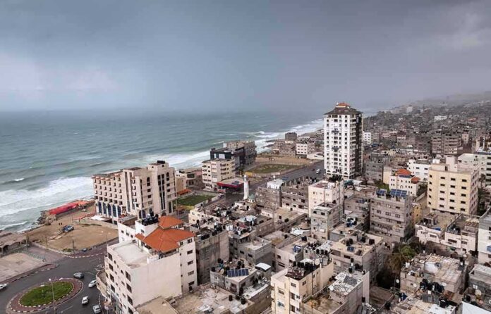 shutterstock_1340771222 Coastal city skyline with mid-rise buildings by a rough sea under overcast skies