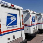 Row of USPS mail trucks parked in a lot