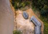Aerial view of riverside huts and canoes beside a muddy river