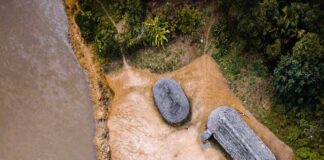Aerial view of riverside huts and canoes beside a muddy river