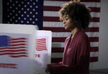Funding Fight Exposes Tensions Inside Texas Democratic Party Voter at a polling booth with an American flag backdrop