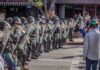Rock Attack Turns Into Federal Prison Riot police in helmets and shields form a line on a city street