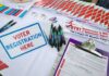 Voter registration table with forms, pens, and informational materials