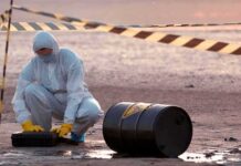 Five Arrested Near U.S. Bomber Base Hazmat worker kneeling near a fallen barrel at a cordoned-off site