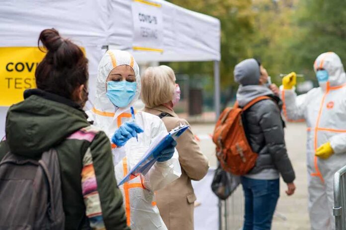 Healthcare workers in PPE assist people at an outdoor COVID-19 testing site