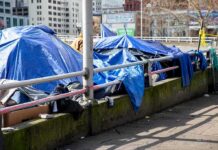 Hidden Underground Encampment Discovered After California Fire Tents covered with blue tarps along a city sidewalk