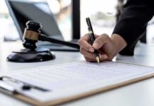 DOJ Rescinds $1.8B Fund in Writing Hand signing legal document beside gavel and laptop