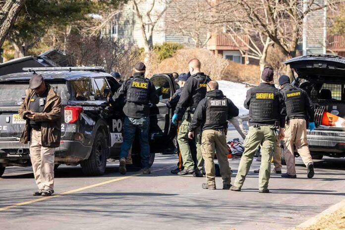 shutterstock_2126536382-1 Police and sheriff officers gather around vehicles on a suburban street