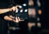 Hands holding a film clapperboard on a dark set