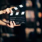 Hands holding a film clapperboard on a dark set