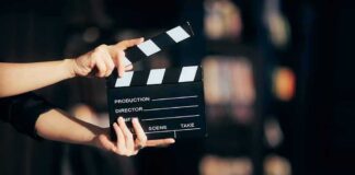 Hands holding a film clapperboard on a dark set