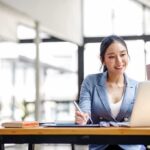 Woman working on a laptop while holding a mug
