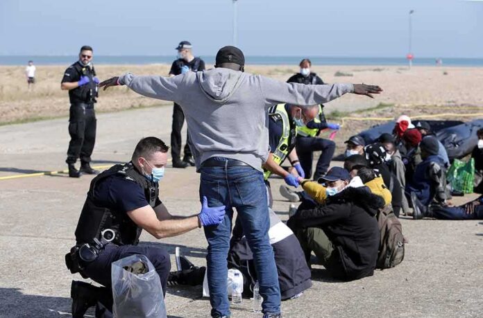 Police officers process group of people on a beachside pavement