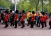 Guards in red uniforms escort a horse-drawn ceremonial carriage