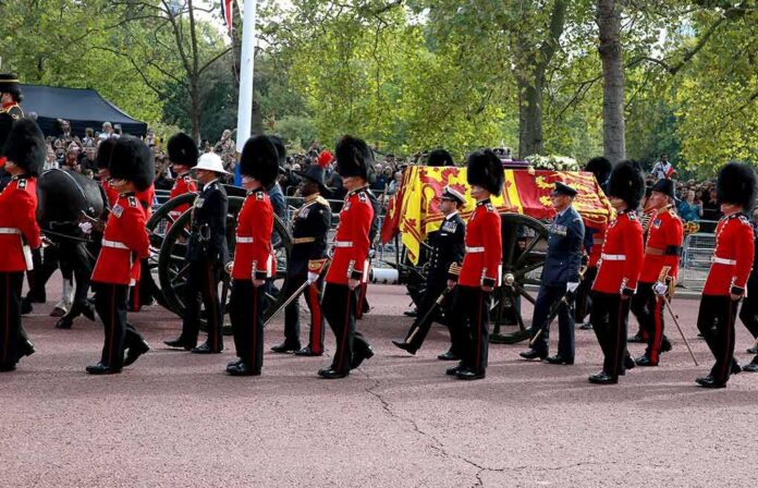 shutterstock_2202241855 Guards in red uniforms escort a horse-drawn ceremonial carriage