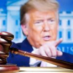 judge’s gavel with a blurred person pointing in the background