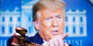 judge’s gavel with a blurred person pointing in the background